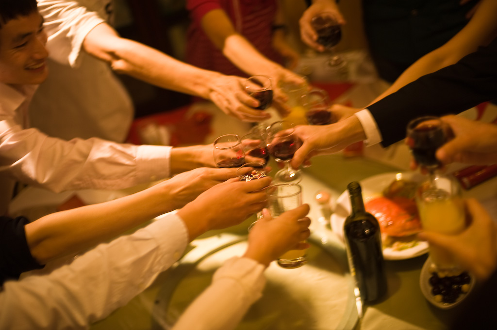 people are sitting and toasting with wine glasses in their hands