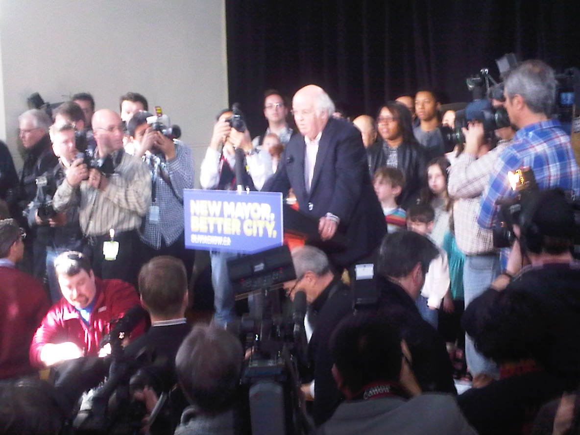 an image of a man speaking into microphones
