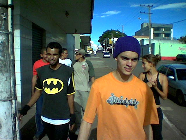 a bunch of guys with a batman t - shirt on, and one is talking on his cell phone