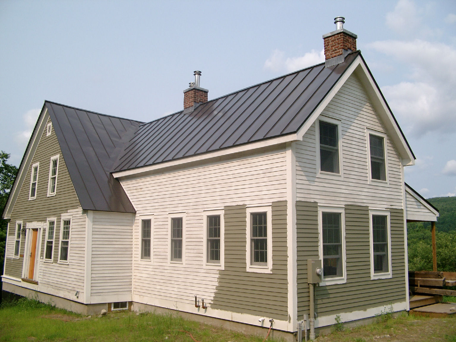 a white house with a metal roof and two windows