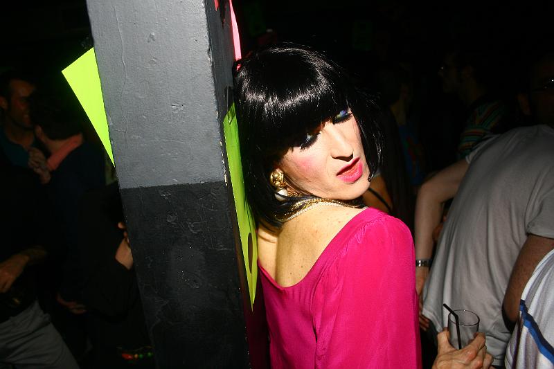 a woman leaning up against a column in a pink dress