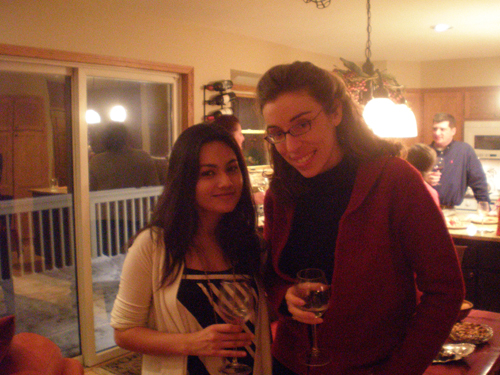 two women standing next to each other while holding wine glasses