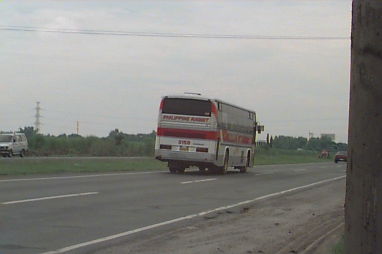 two buses driving down the road and a few cars going around