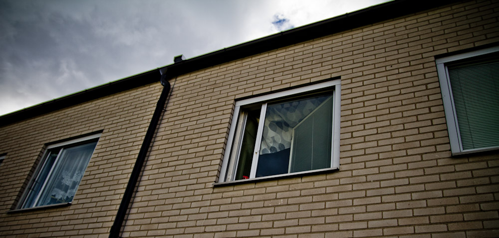 the brick building has a window with a weathervane on the side