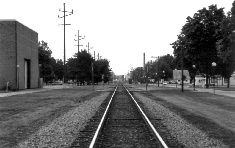 black and white pograph of train tracks near an empty road