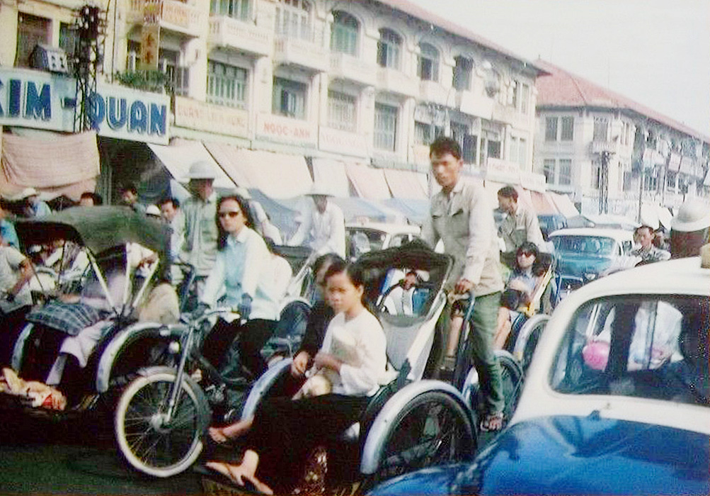 many people ride in rickshaws down a crowded street
