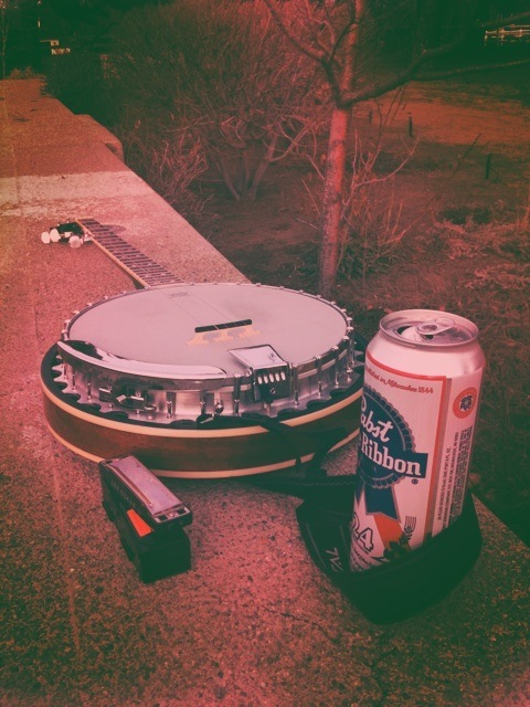 a can and a can of beer sitting on top of a cement wall