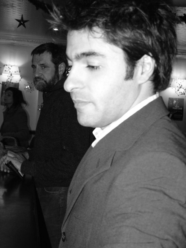 a man looking to his left, with two other men in the background