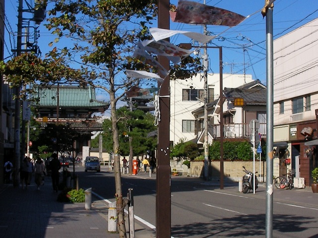 a clock on a metal pole next to a street