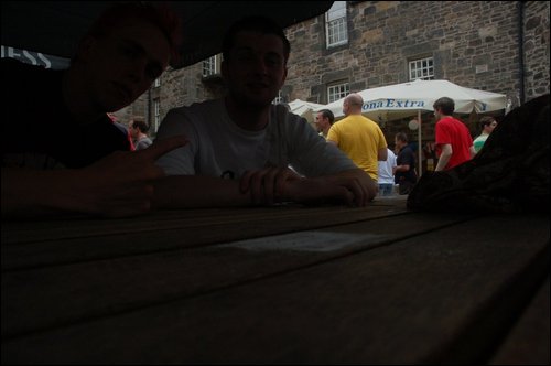 men sit on a picnic table in the middle of a crowd