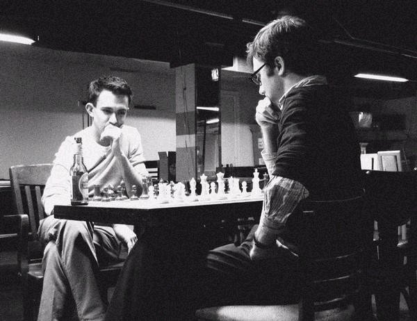 two men sitting at a table playing chess
