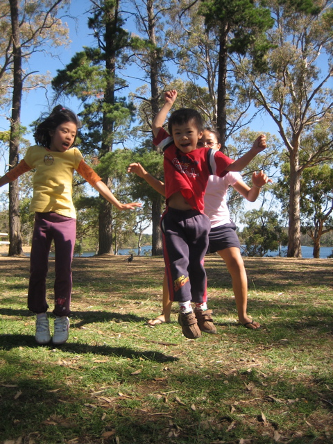 three young children playing frisbee in the park