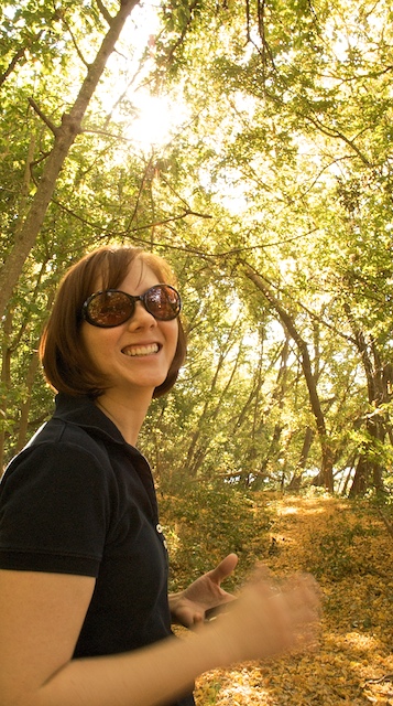 a woman wearing shades standing near some trees
