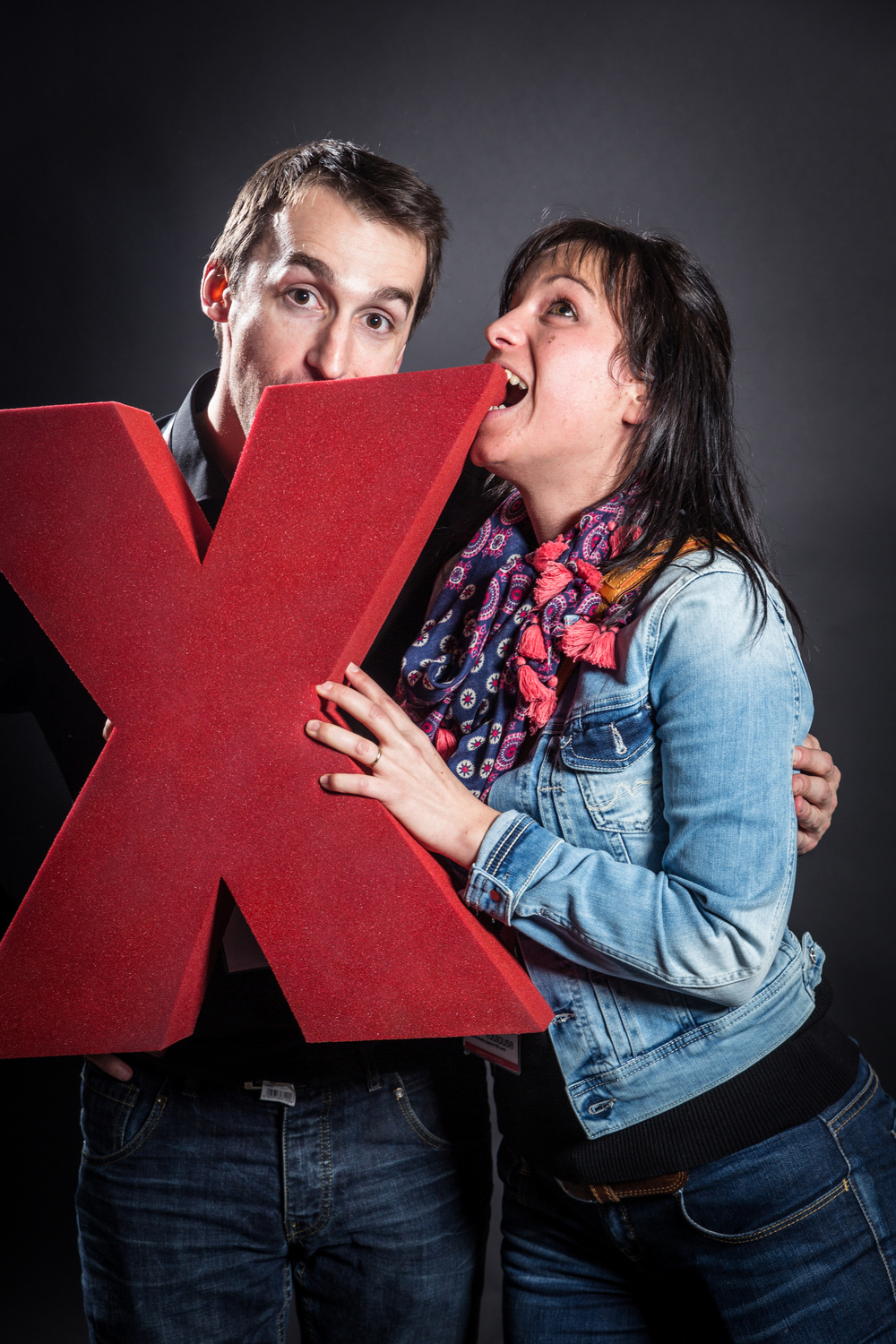 two people making a silly face while holding a x symbol