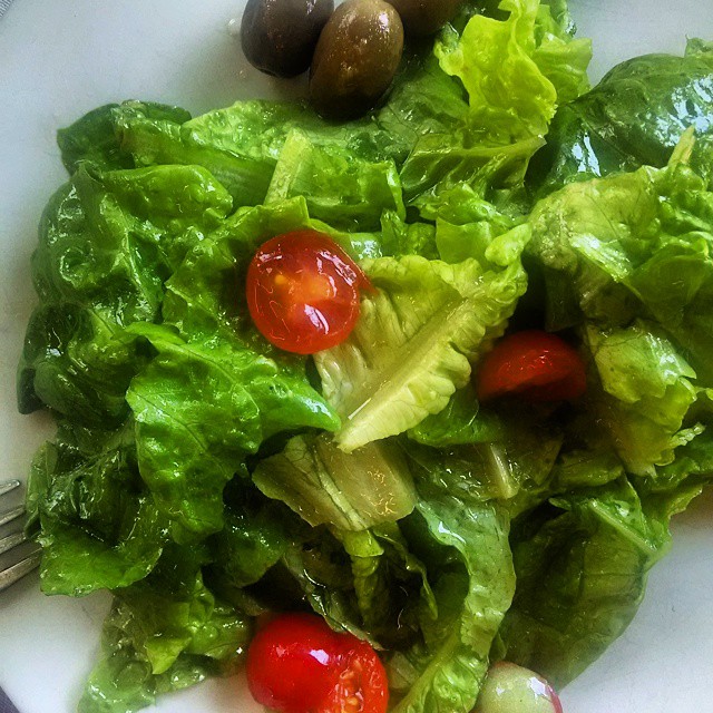lettuce with tomatoes and olives on a white plate