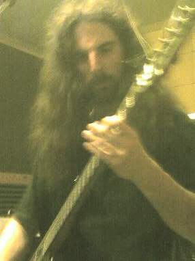 a bearded man is playing a guitar at the recording studio
