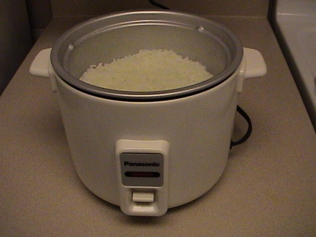 a rice cooker on top of a counter with a bowl of rice in it