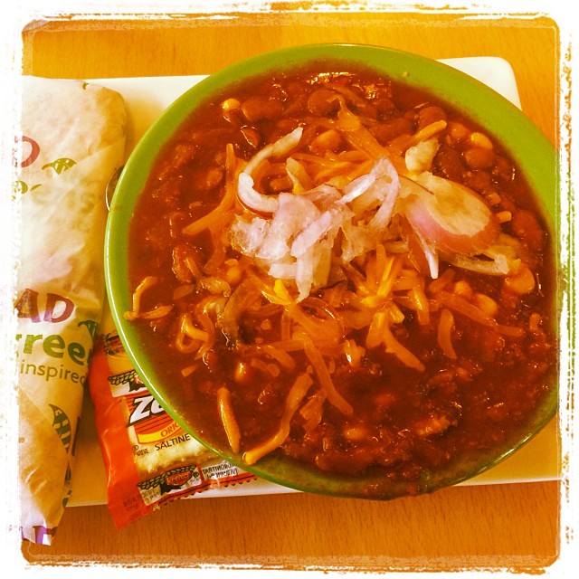 a bowl of chili with beans and onion on the side