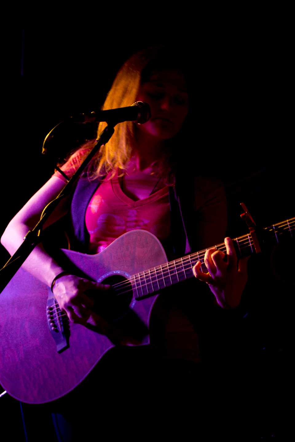 a woman playing a purple guitar at a concert