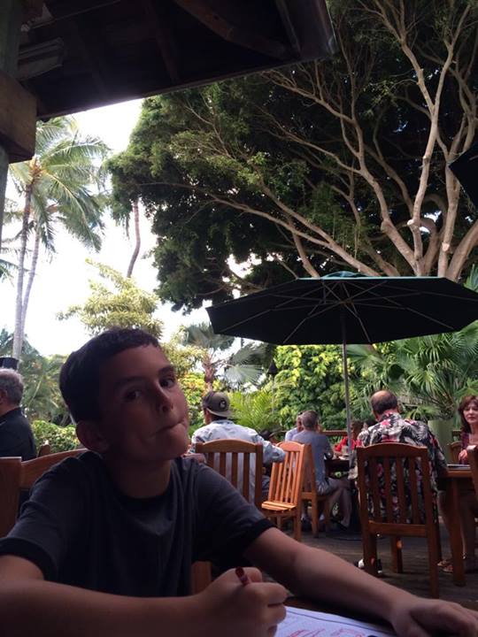 a boy sitting in a cafe, smiling for the camera