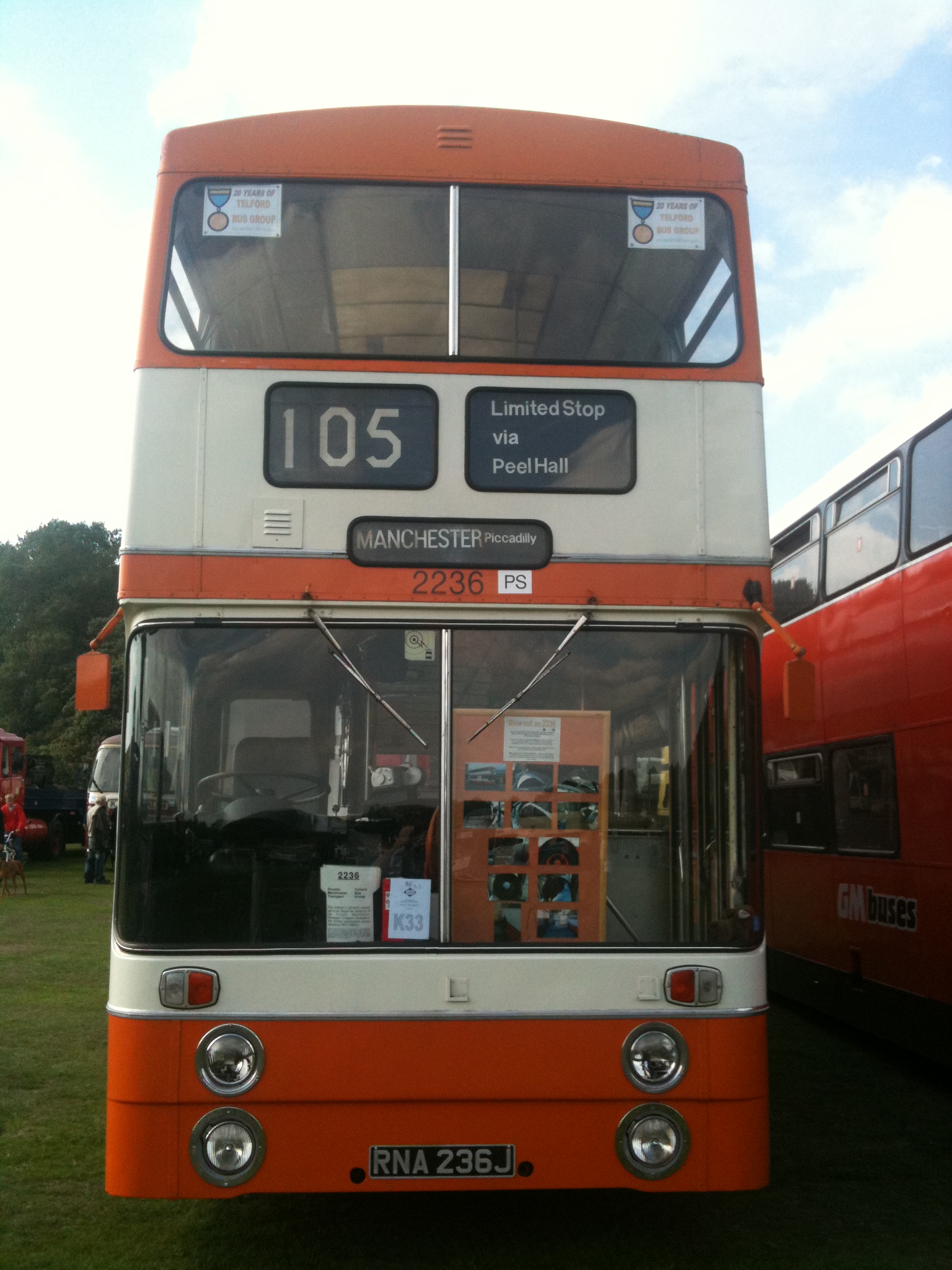 an orange bus sits at the front of two other buses