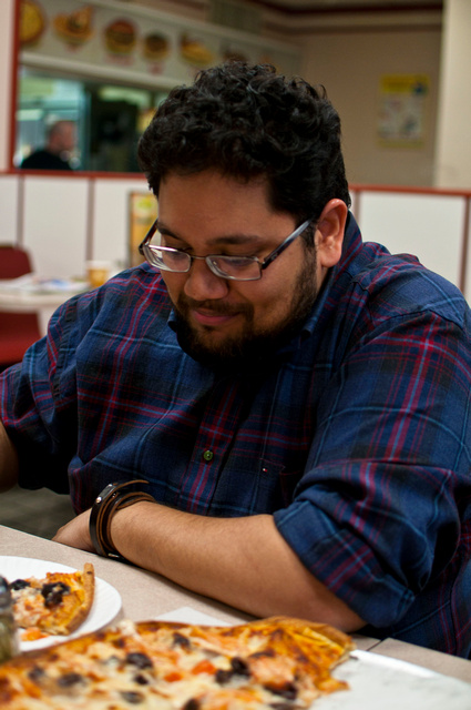 a man sits at a table with a plate of pizza