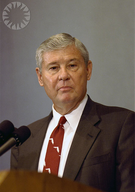 a man with grey hair wearing a suit and red tie