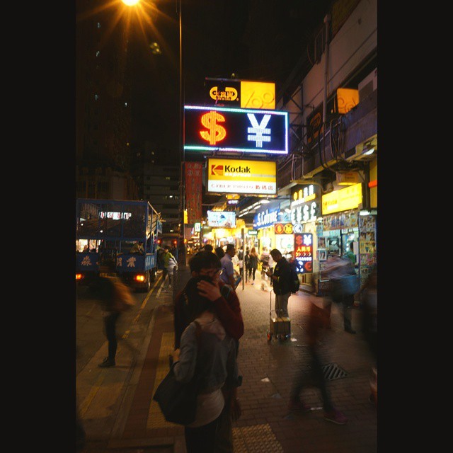 people walking along the sidewalk near buildings at night