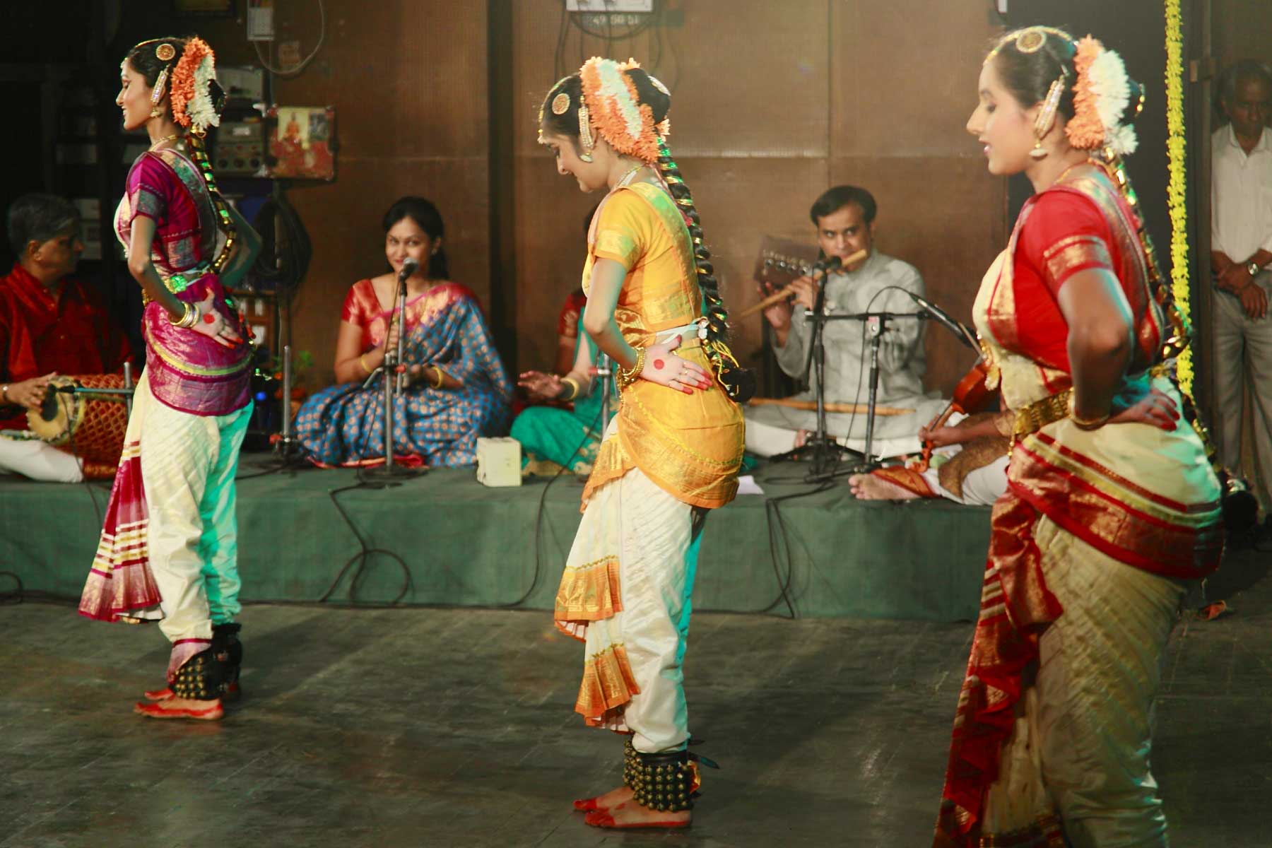 women performing a dance in colorful clothing and holding garlands