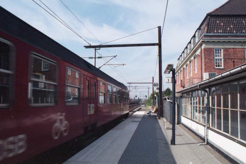 a red train sitting next to a building