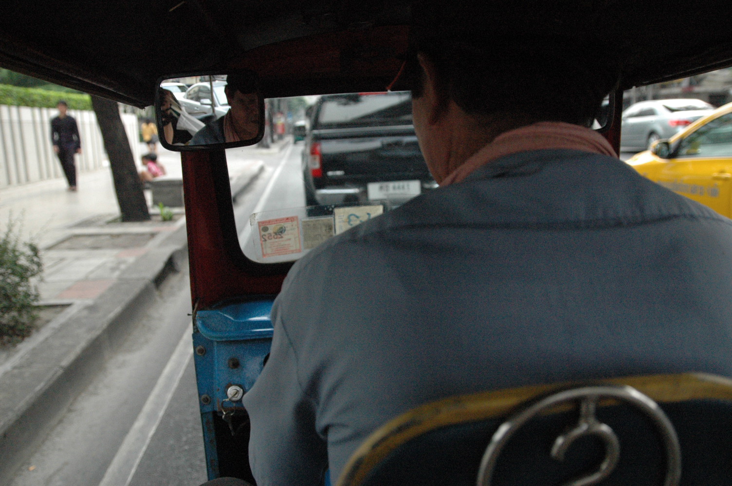 a man driving a tuk tuk down a street next to traffic