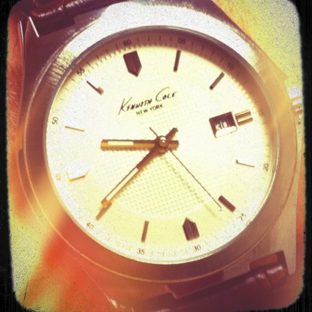 a watch with gold hands and brown leather straps
