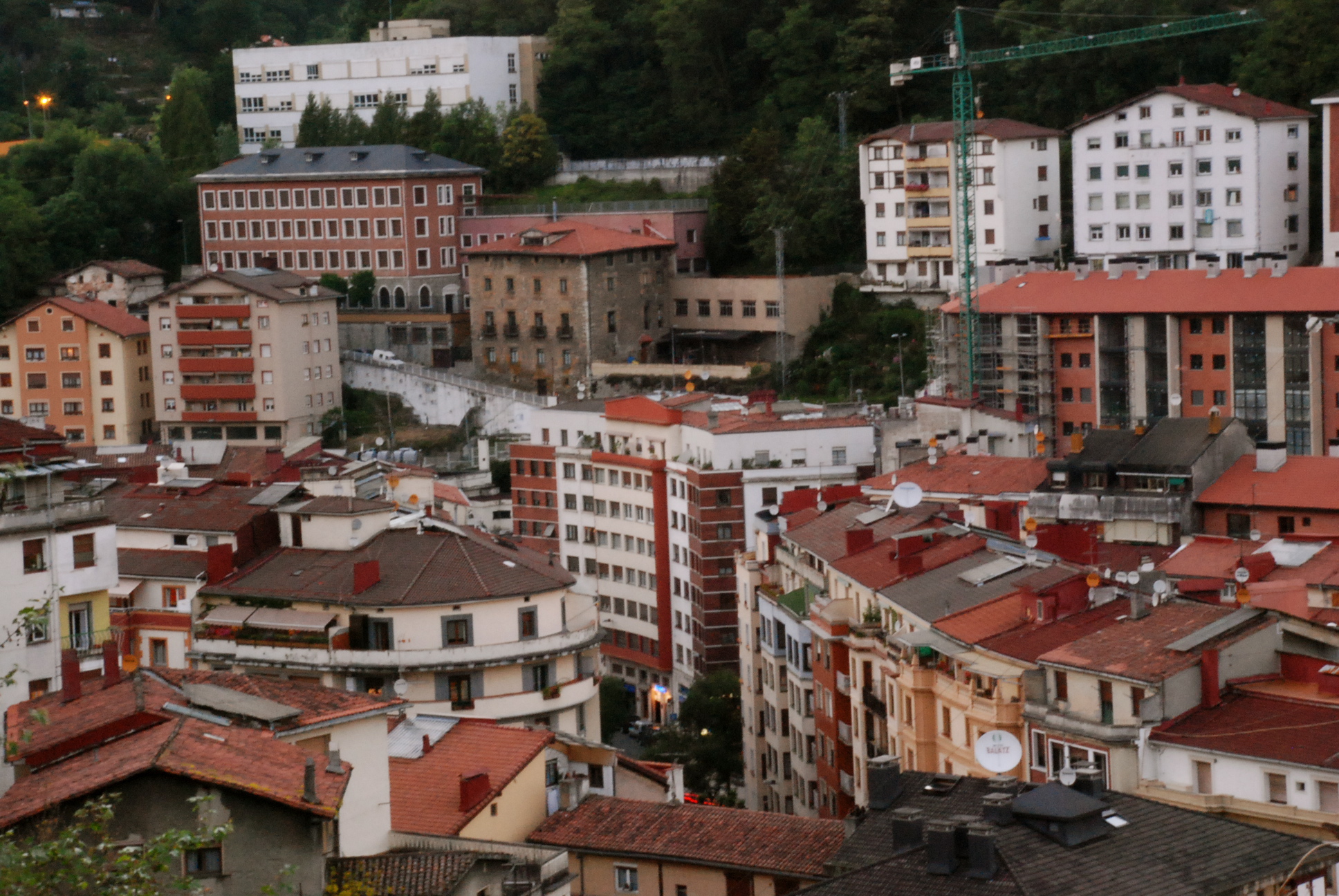 a city with some red roofs and mountains in the background