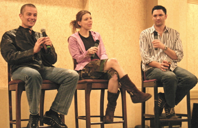 four people are sitting on a chair in front of a microphone