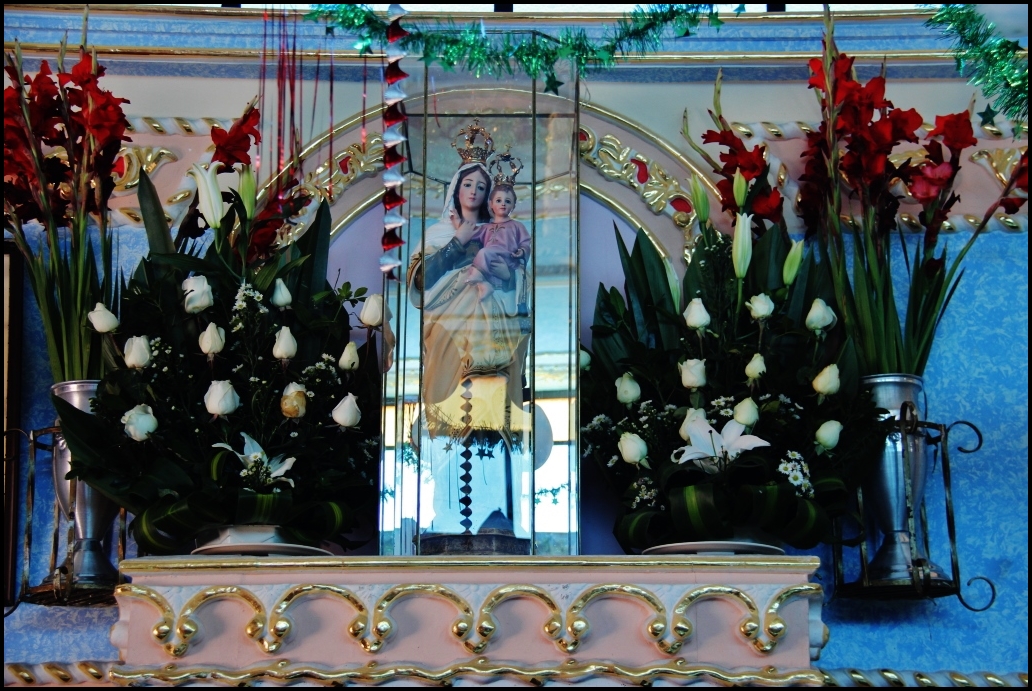 there is a shrine with flowers and a mirror on the shelf