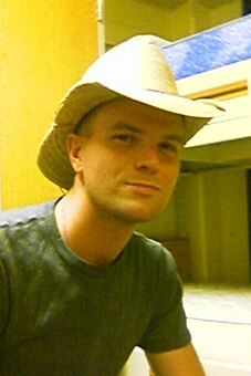 a man wearing a cowboy hat sitting next to bunk beds