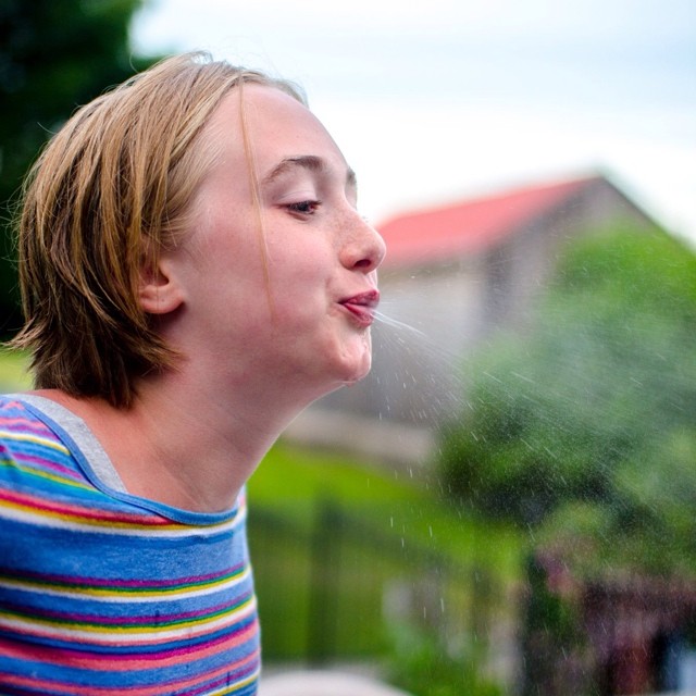 a woman wearing striped shirt blowing bubbles from her nose