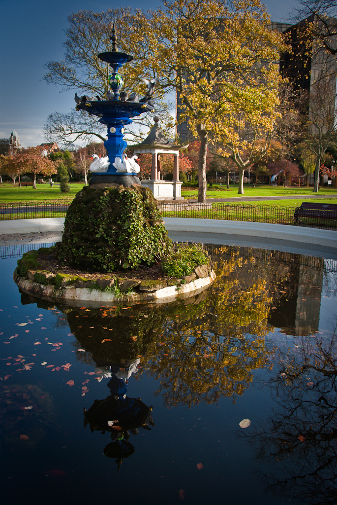 a large birdbath in a park with trees