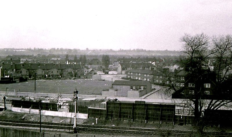 an old pograph with buildings and a railway on the left