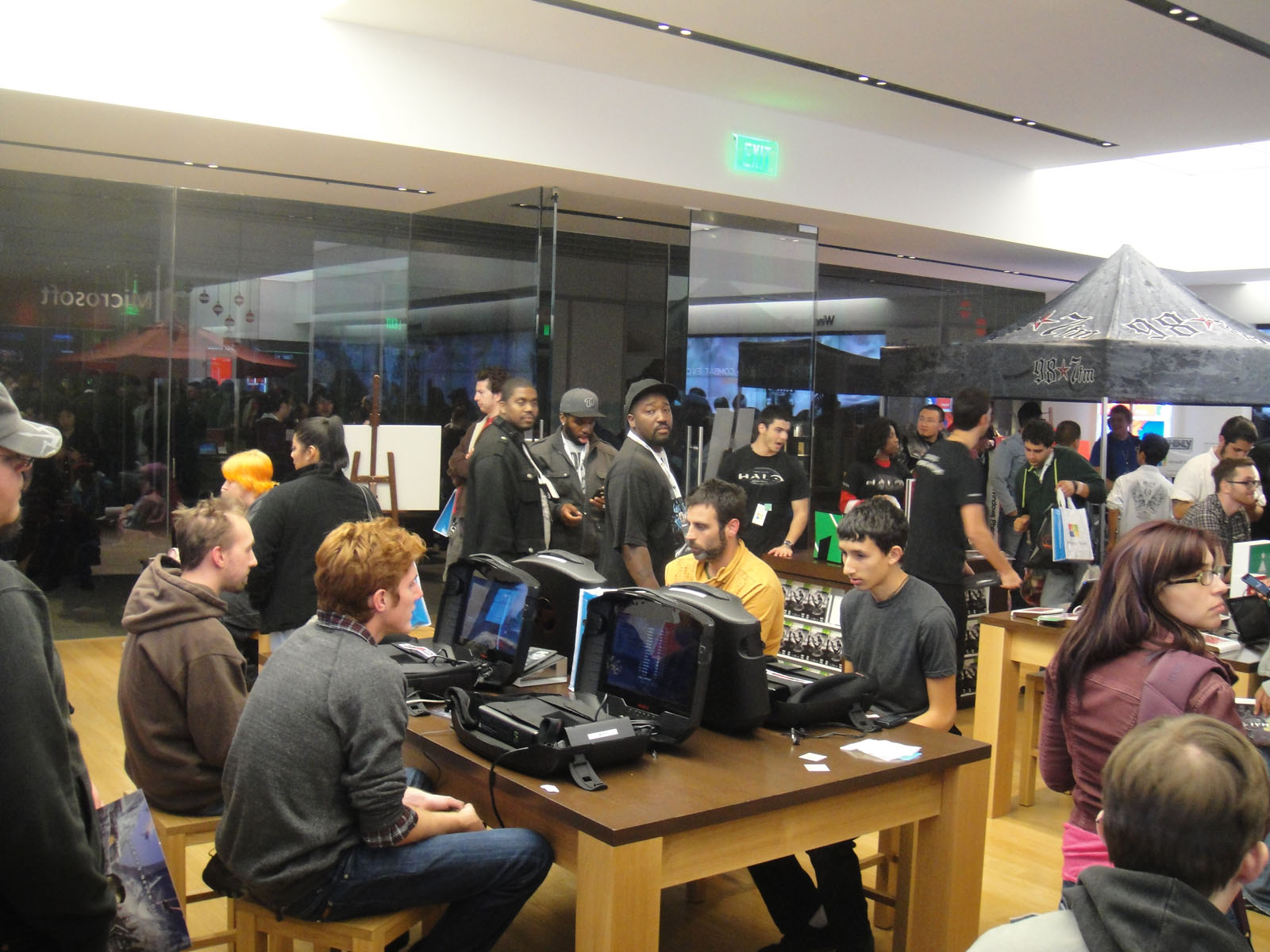 people looking at various computers and electronic devices on tables