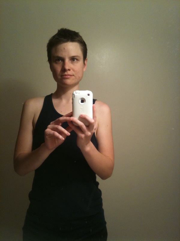 a girl in a black tank top takes a selfie in the mirror