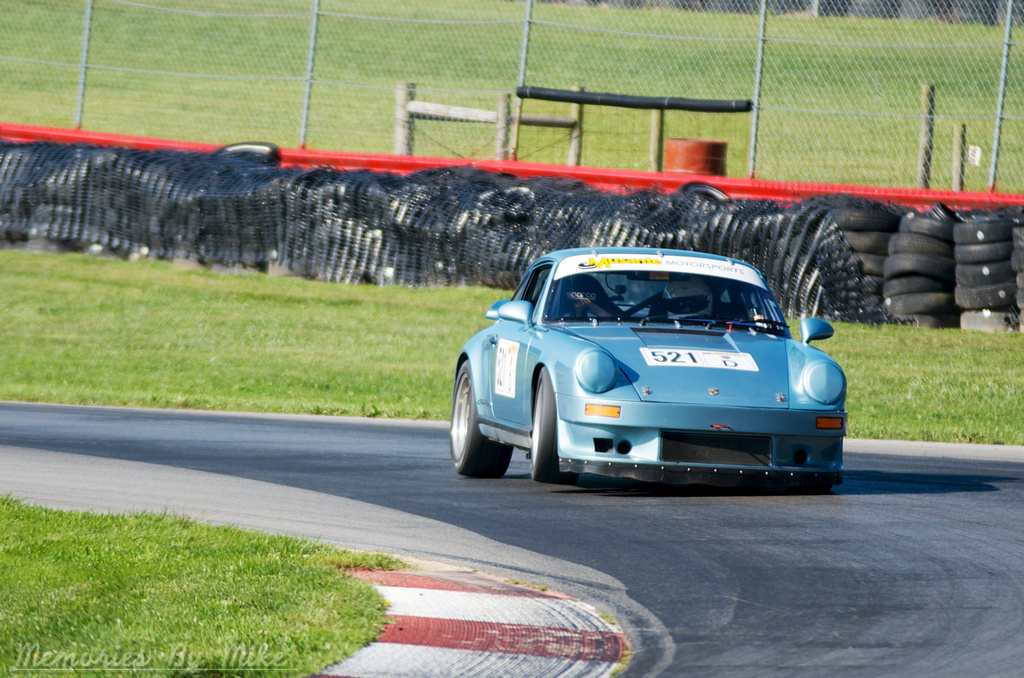 a blue racing car driving on a track near a field