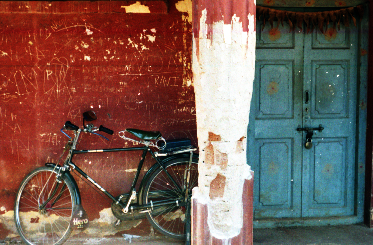 the bike is leaned against the red wall