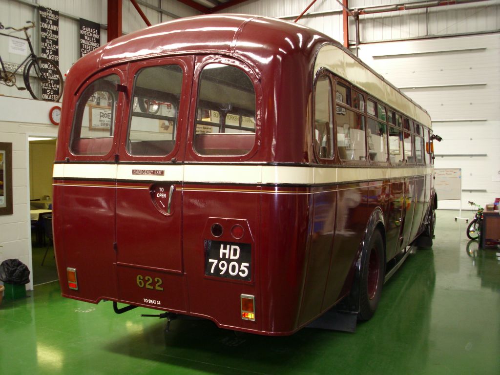 a red and white bus parked inside of a garage