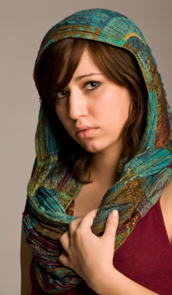 a woman posing in a scarf and holding a purse