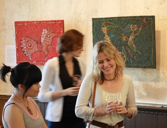 two young women enjoying paintings in an art gallery