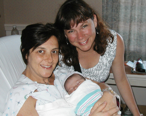 two women are smiling for a picture with a baby in a hospital bed
