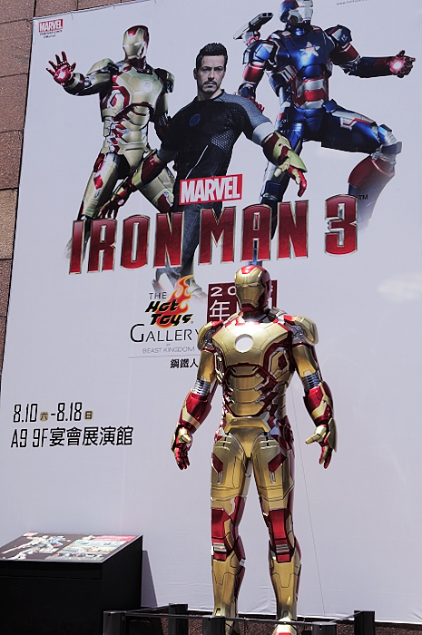 an iron man suit on display next to a giant movie poster