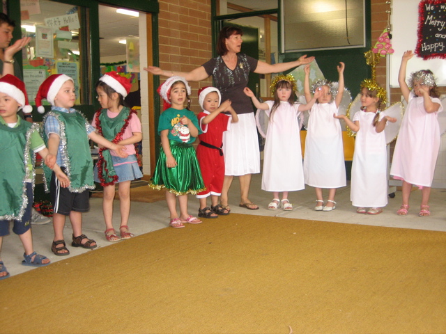 some children in dresses and costumes standing up with their hands in the air