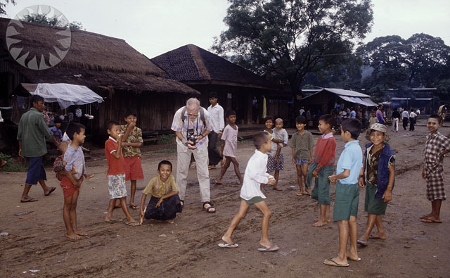 people standing around in the dirt by a hut